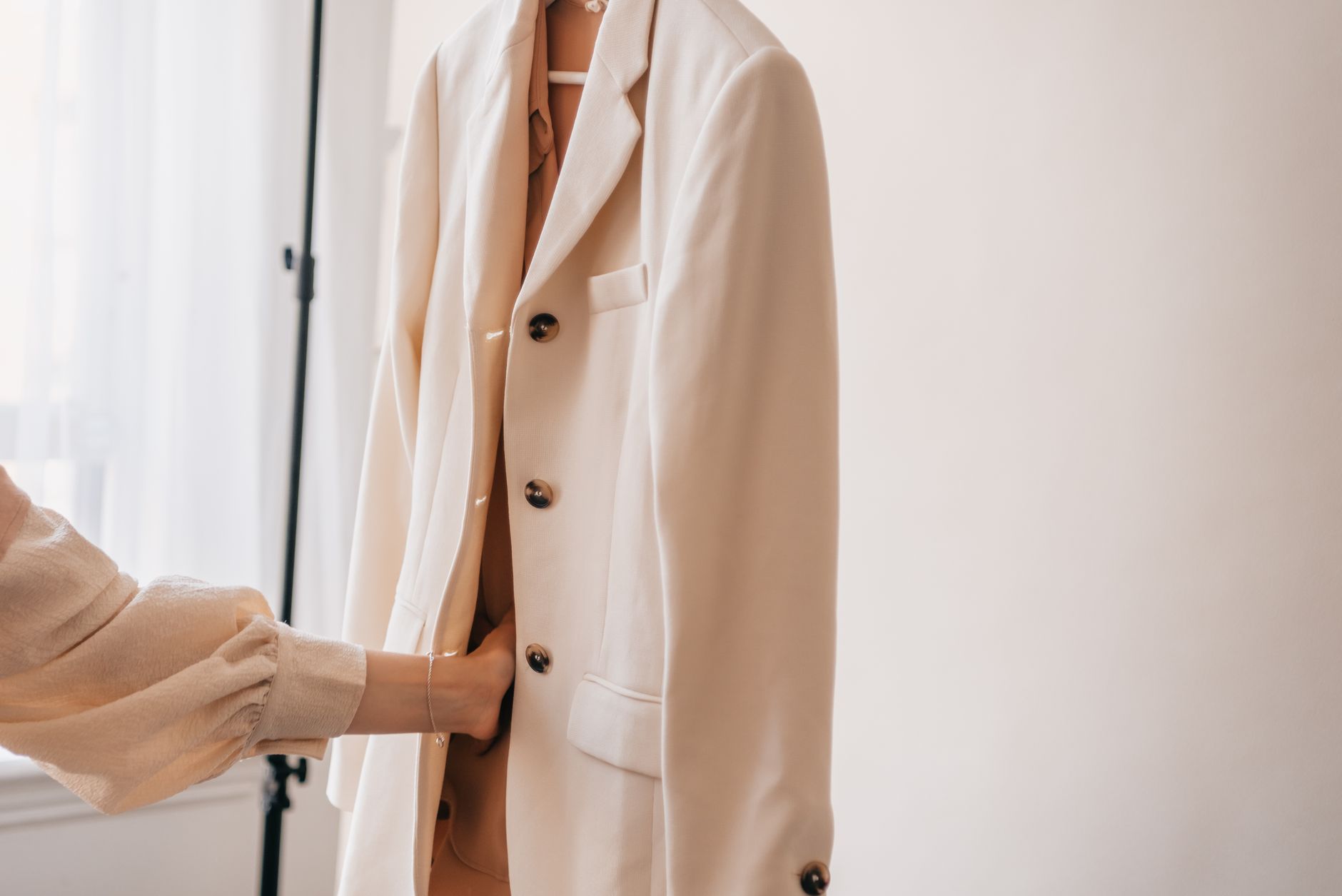 Veste de tailleur blanc pour mariée suspendue sur un portant